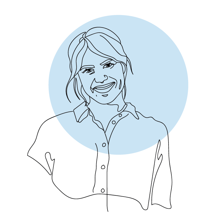 Ein Foto. Eine weiblich gelesene Person steht seitlich mit verschränkten Armen, der Kopf ist zur Kamera geneigt. Sie lächelt.